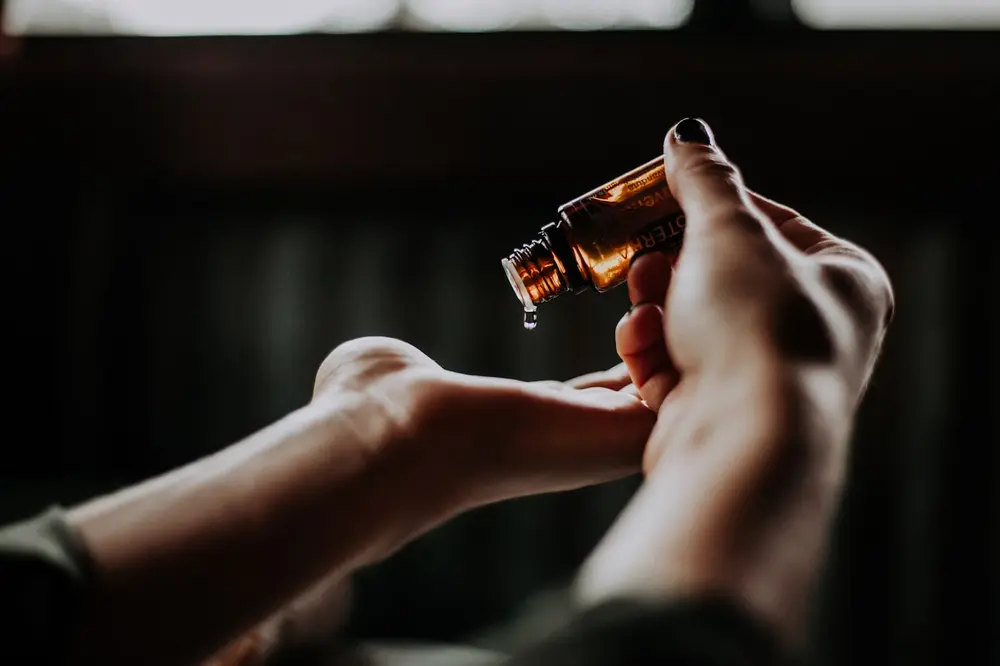 Hands warming a dropper of facial oil in low evening light