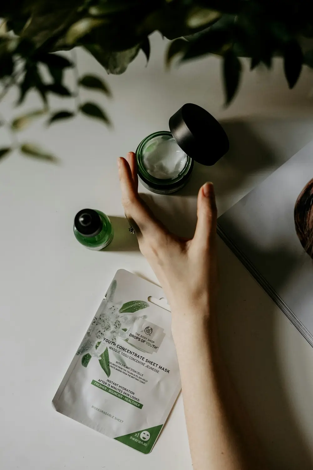 Hand reaching for a green skincare product from above, mid routine