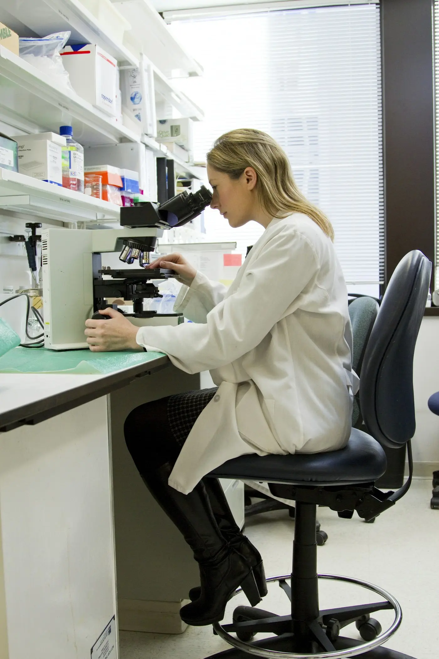 Researcher in a white coat working at a microscope in a laboratory